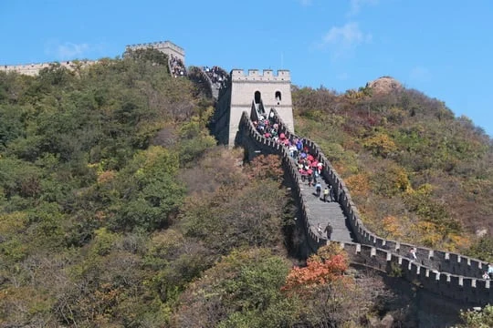Visitors walking between Mutianyu Great Wall watchtowers above wooded slopes